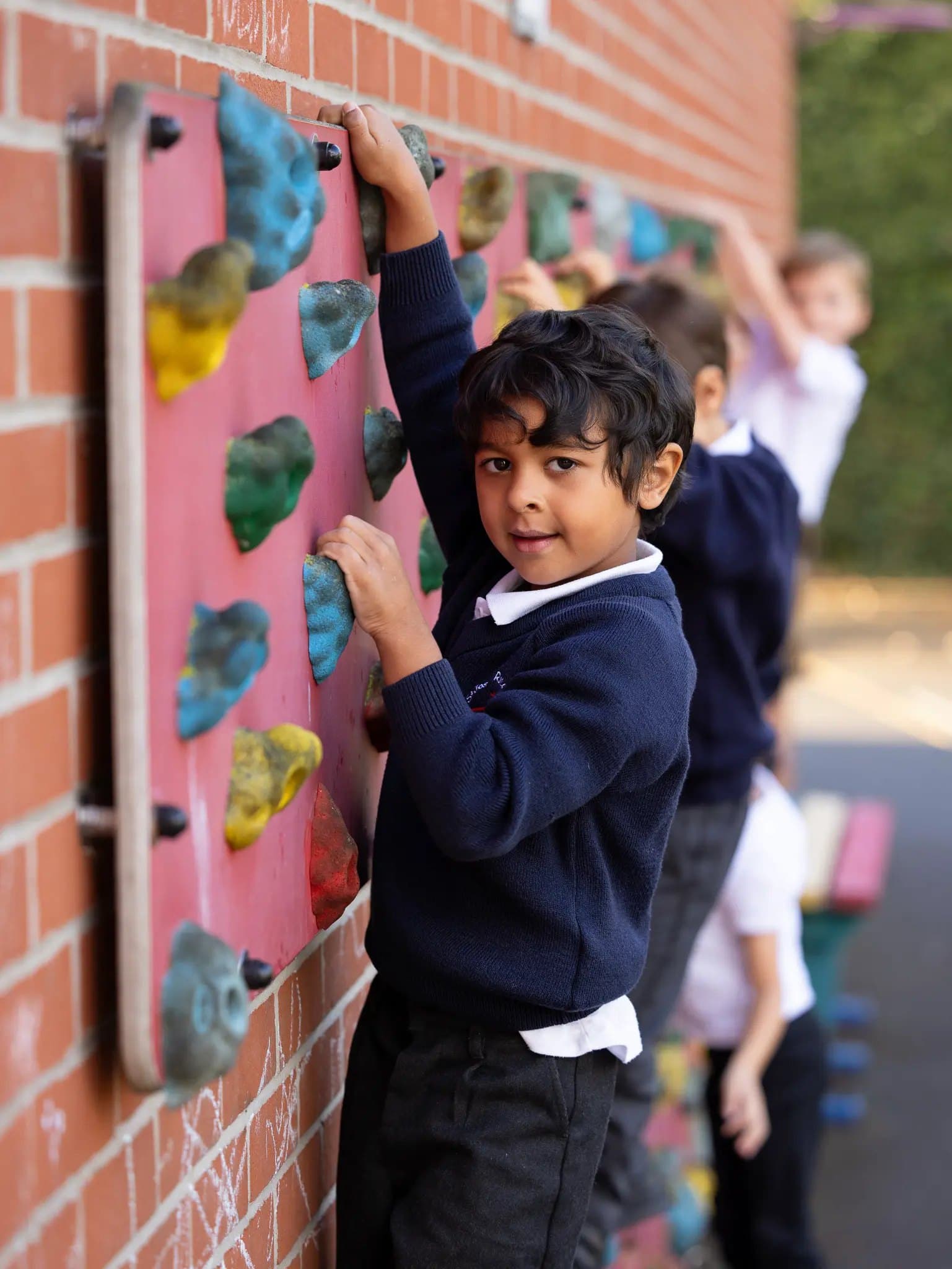 A young pupil on the playground climbing wall