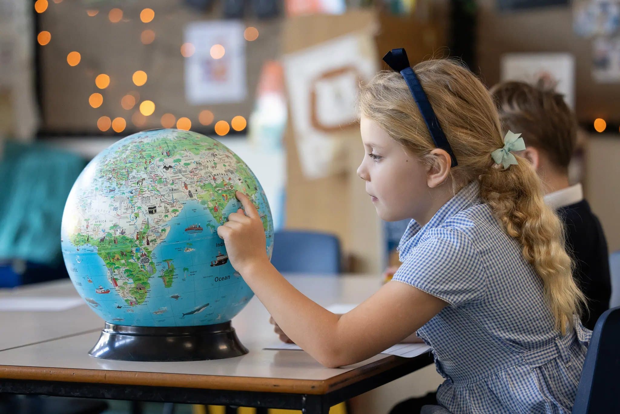 A girl exploring a globe in her classroom