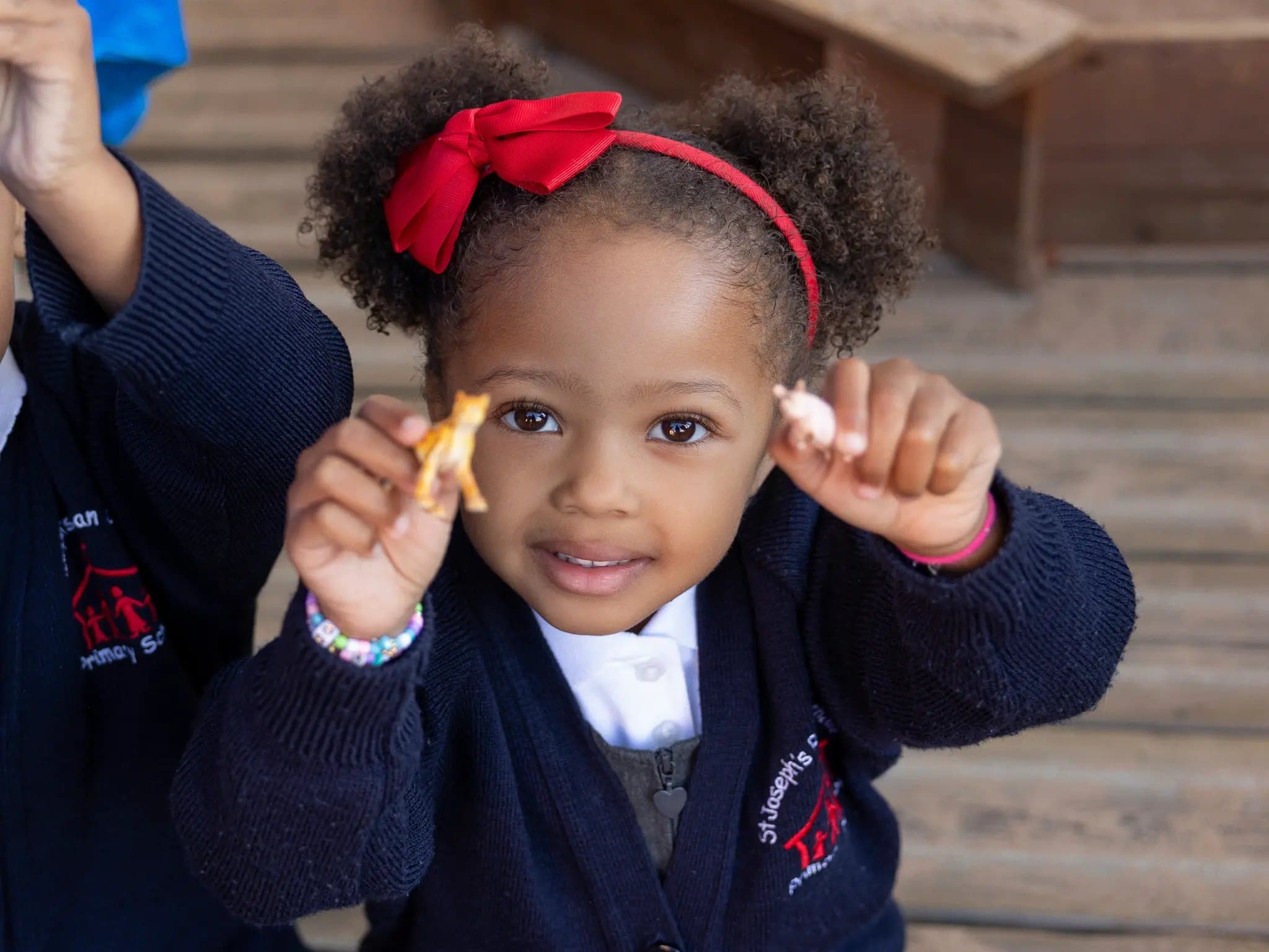 A young pupil smiling as she holds up two toy animals