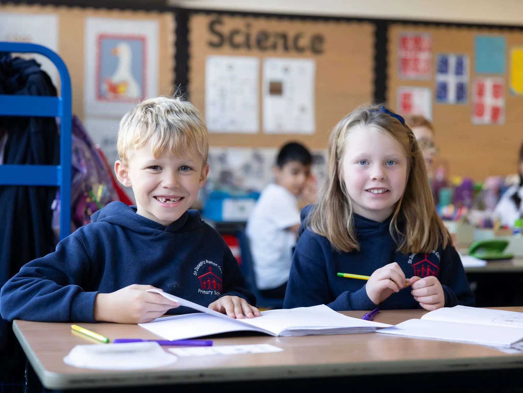 Two smiling pupils working together in class