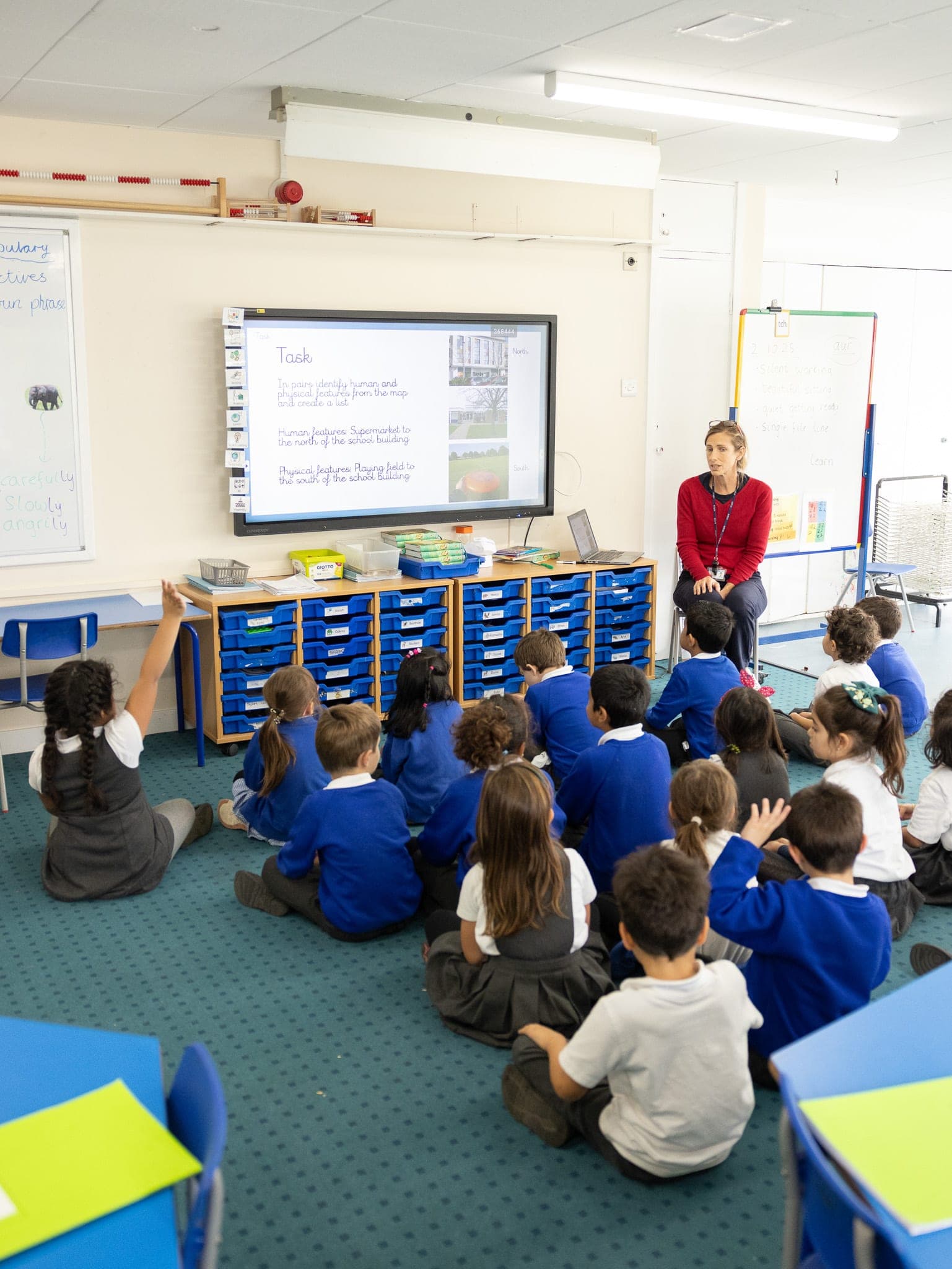 Young pupils sitting on the carpet listening to their teacher
