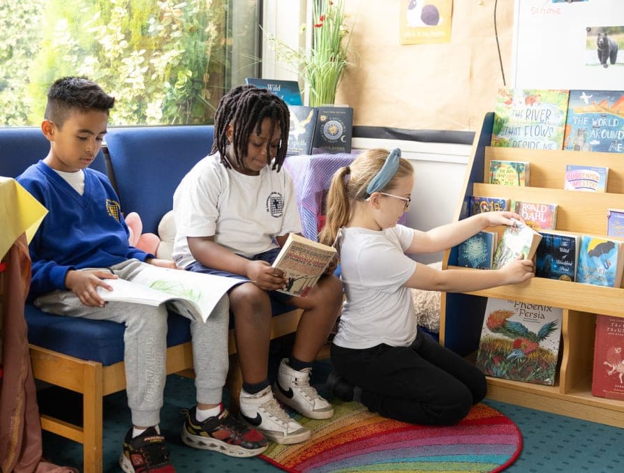 Three pupils reading together in a cosy book corner