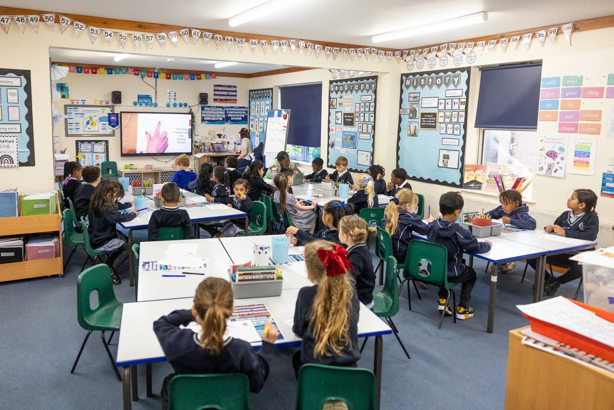 A busy classroom of pupils working at their tables