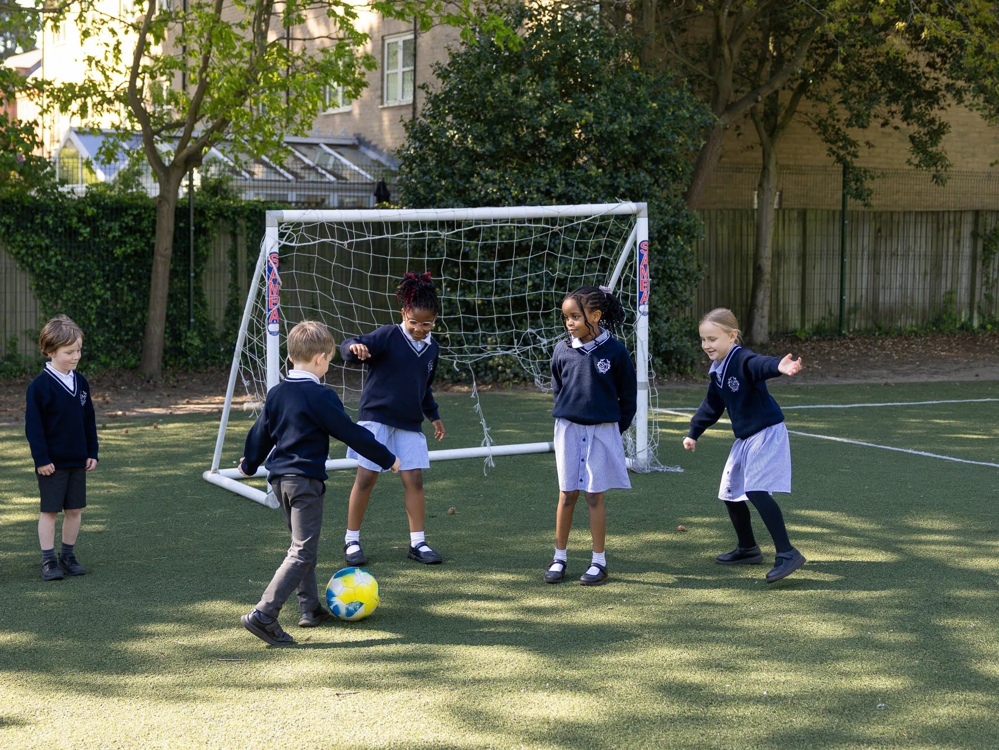 Pupils playing football together on the school pitch