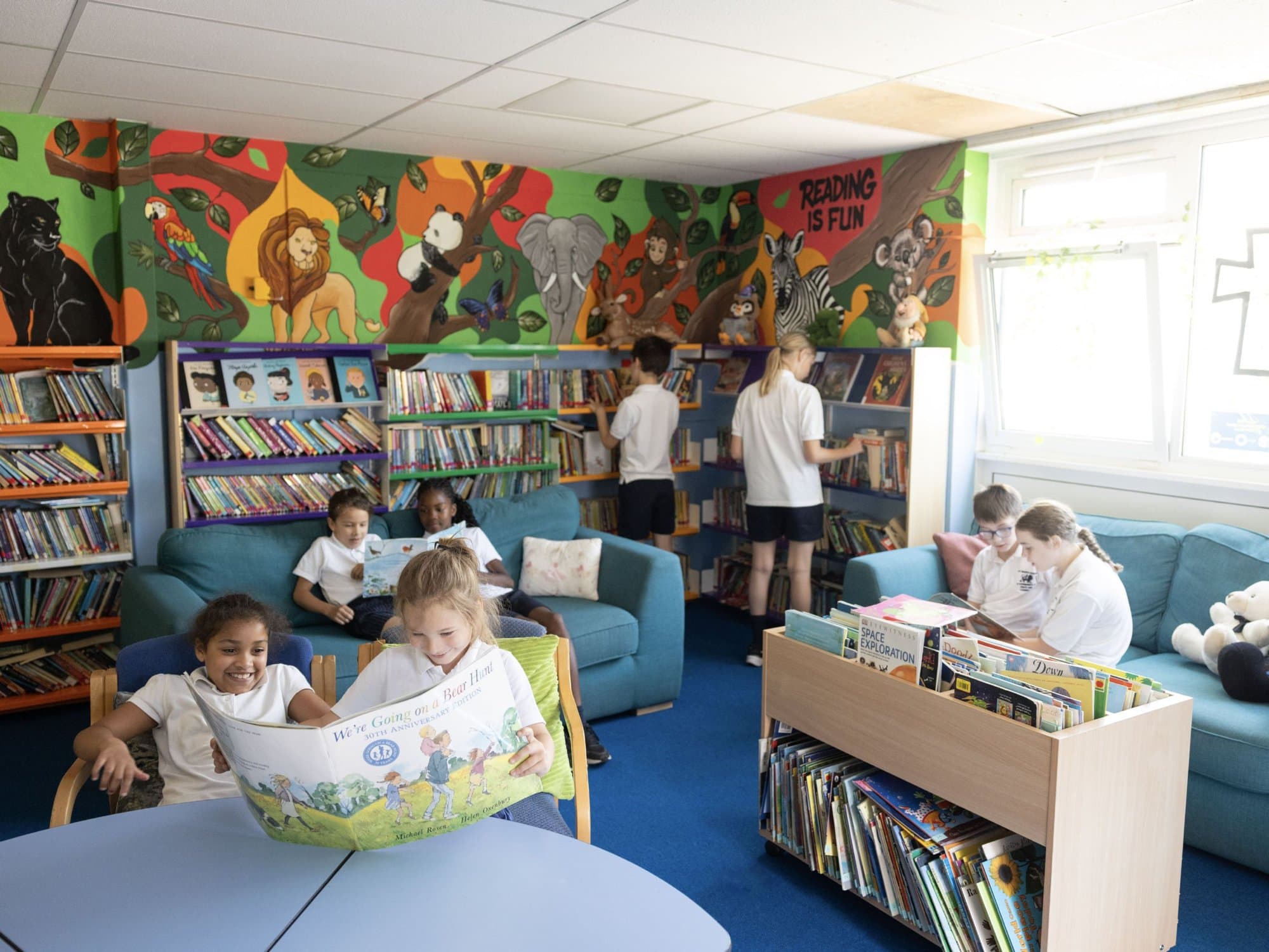Children reading on sofas in the colourful school library