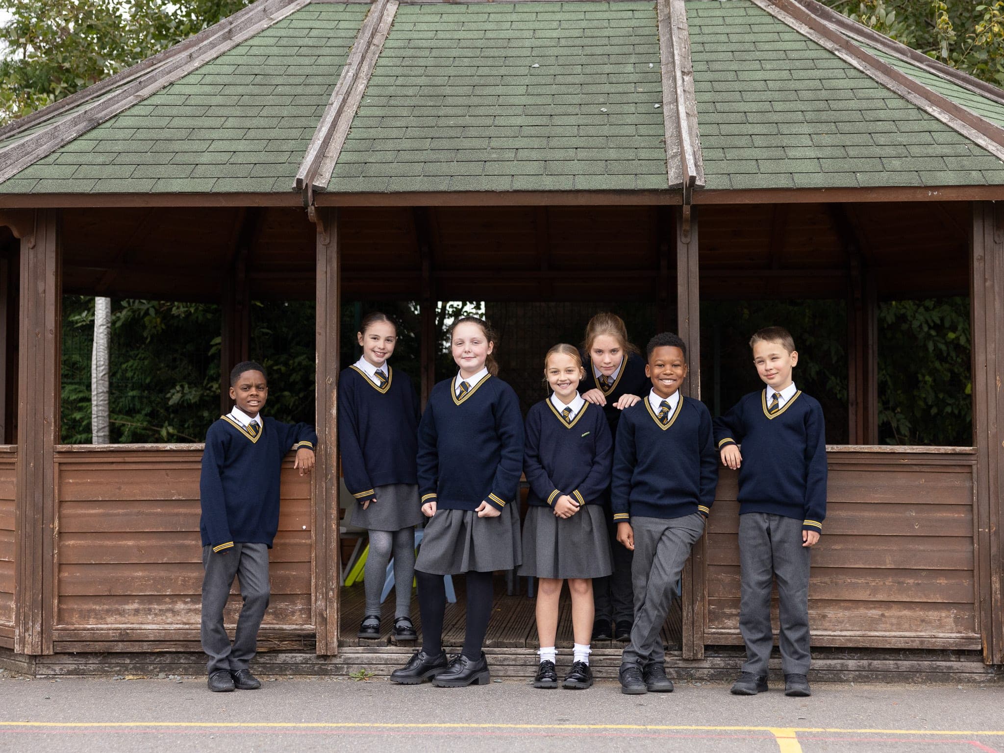 A group of pupils standing together in the wooden playground shelter