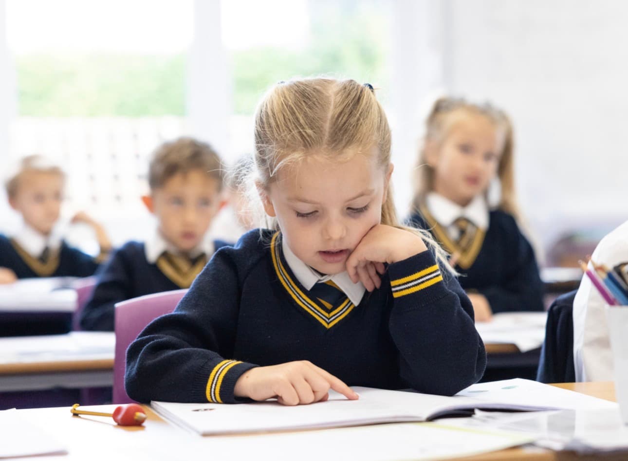 A young girl concentrating on her book at her desk
