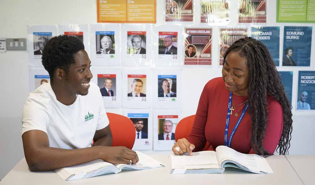 Two students reading together in front of a politics display