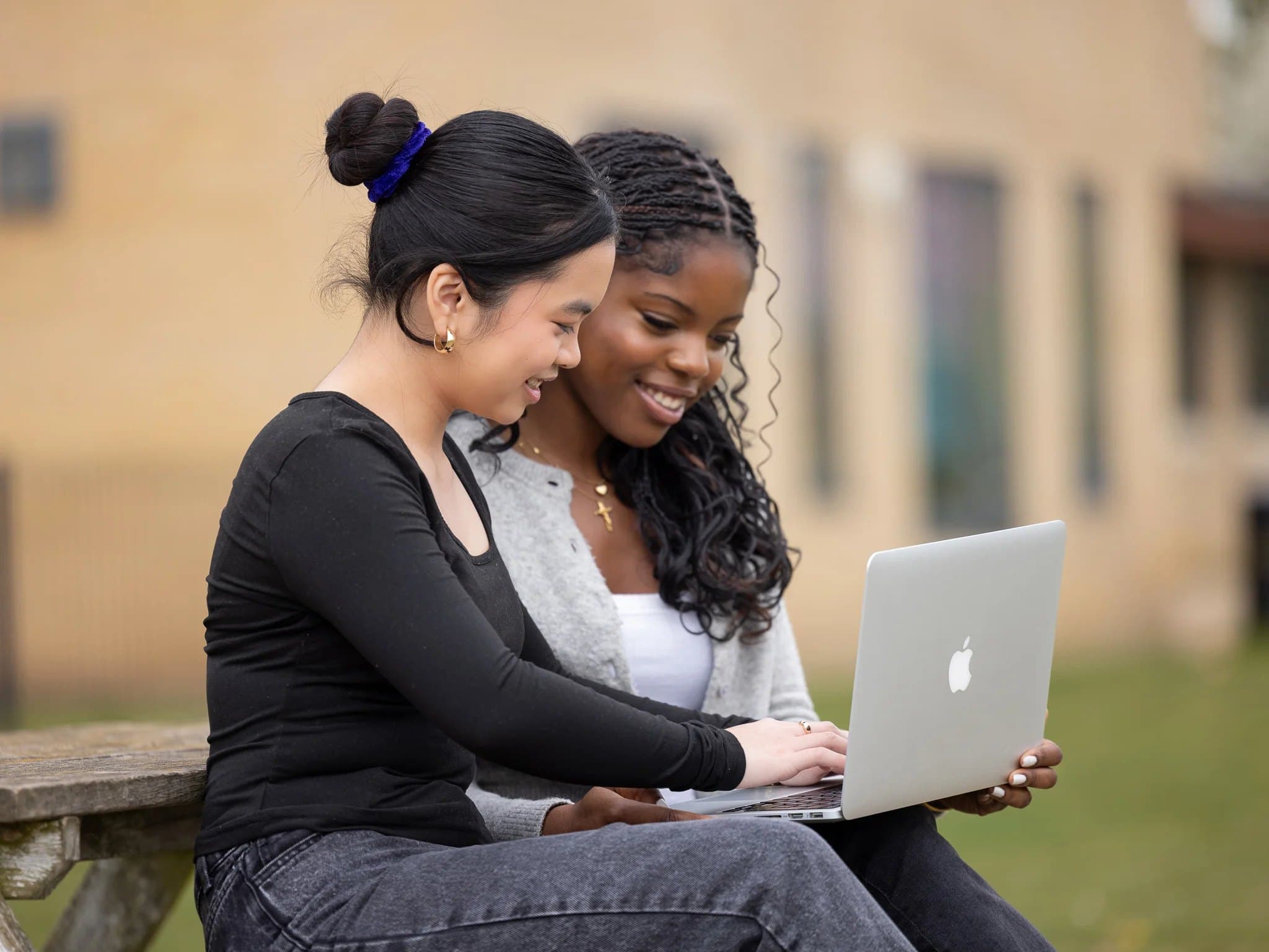 Two students sharing a laptop outside