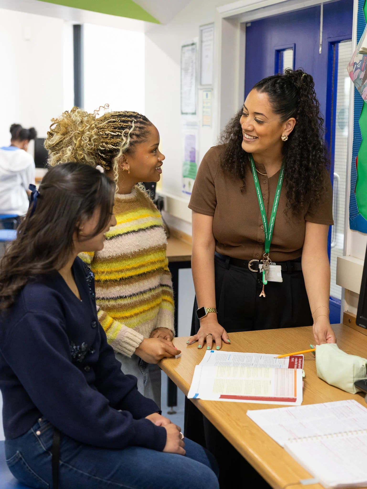 A tutor talking with two sixth form students at a desk