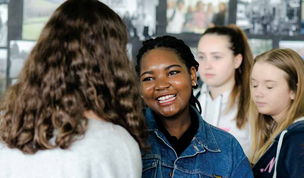 A smiling sixth form student chatting with friends
