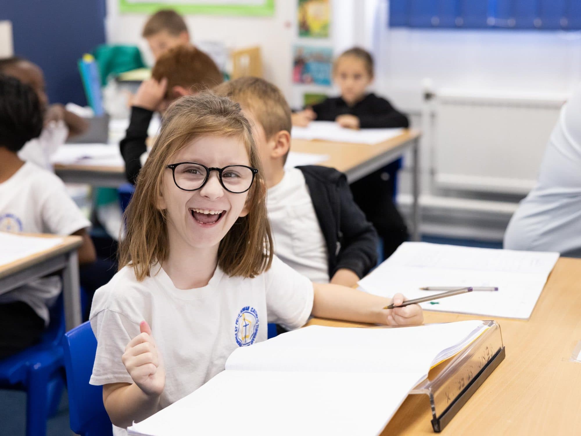 Girl in glasses laughing and giving a thumbs up at her desk